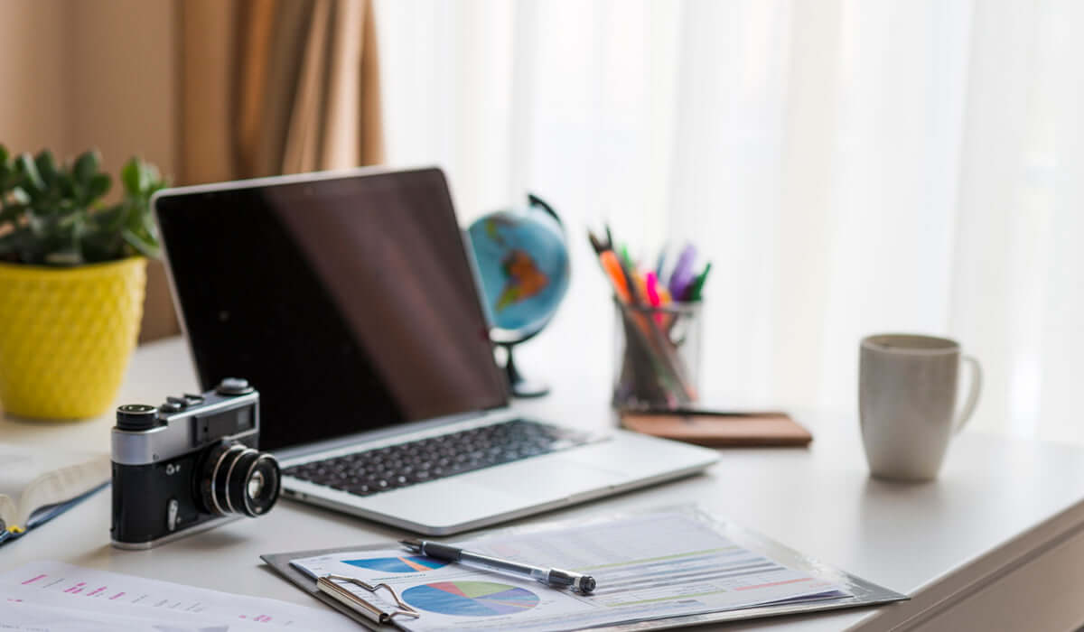 A desk setup displaying a used laptop, camera, and other items.